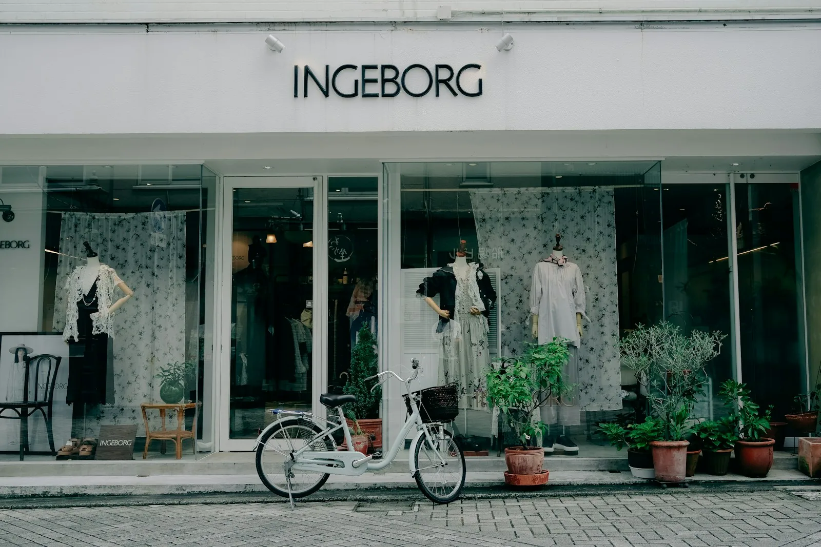 A bright fashion storefront with window displays and a bicycle parked outside
