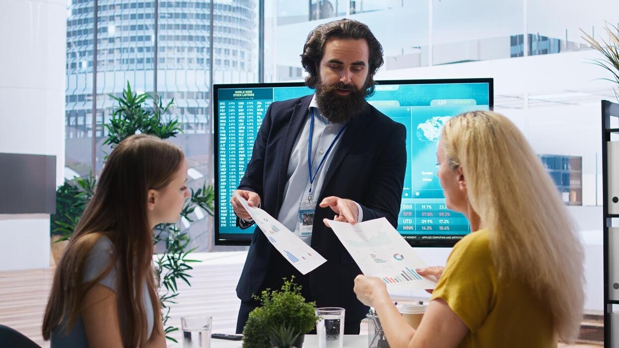 Advisors reviewing an agent-generated exception report in front of a live market board