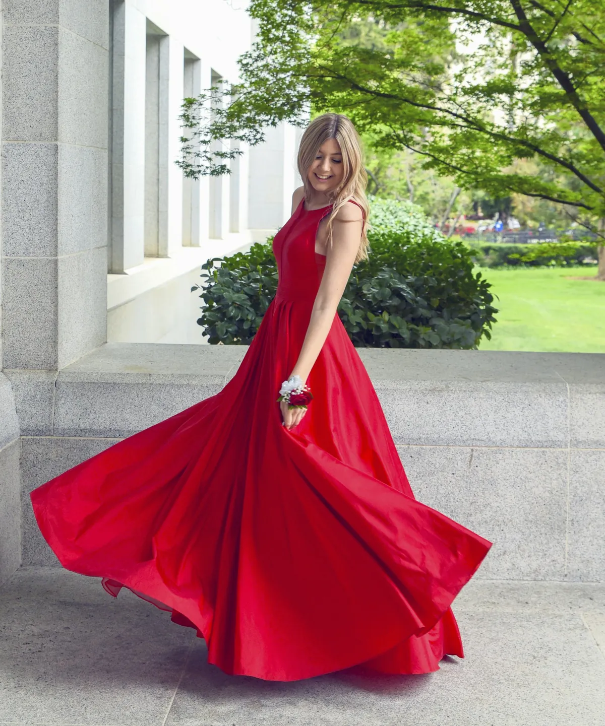 A model in a flowing red dress turning in a garden