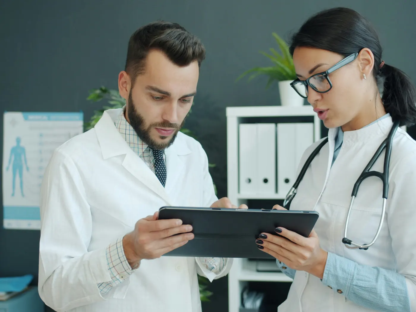 Two doctors in white coats reviewing information on a tablet together