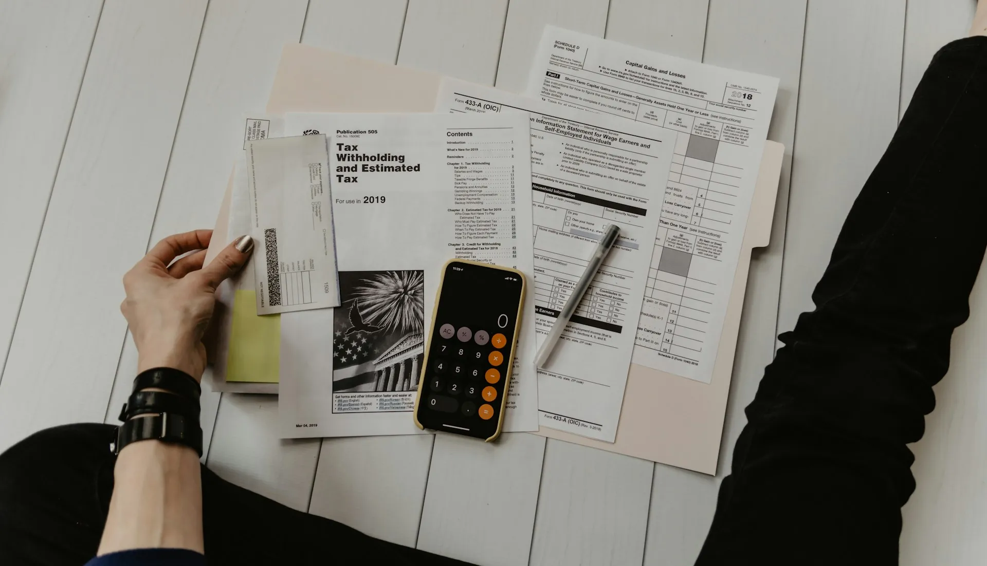 Hands working through insurance paperwork beside a laptop and calculator