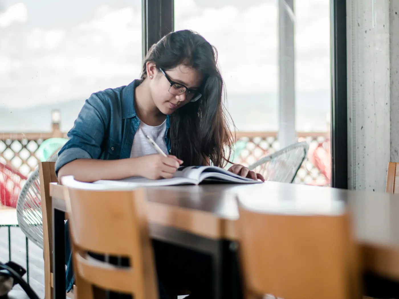 A student taking notes from a textbook at a study desk