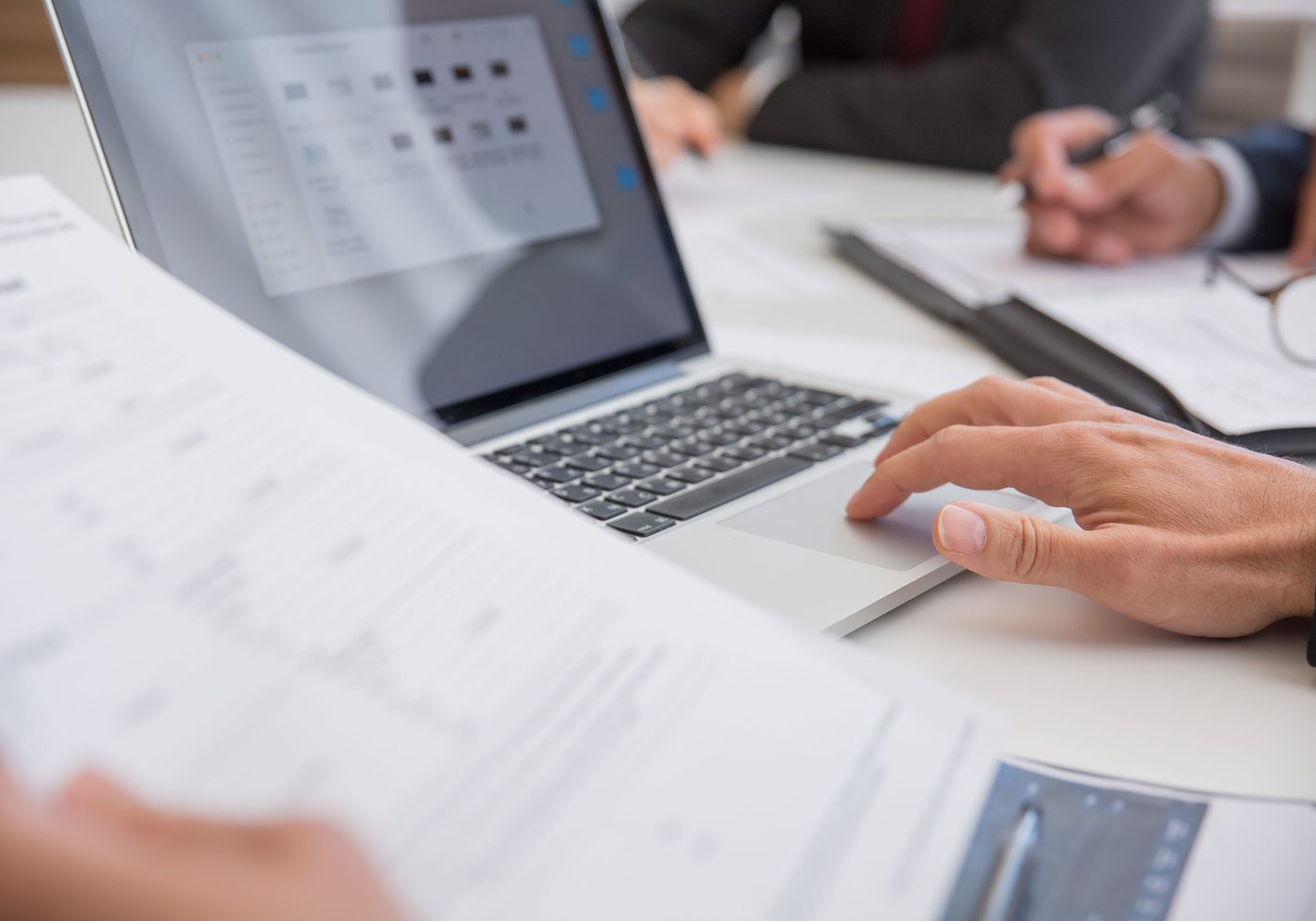 Two consultants reviewing printed reports beside a laptop during a planning session