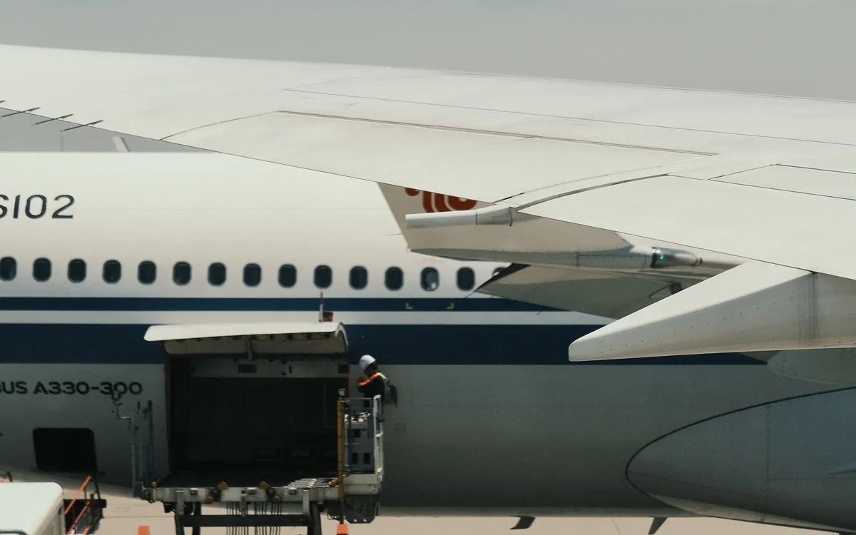 A widebody aircraft being serviced by ground handlers at the gate