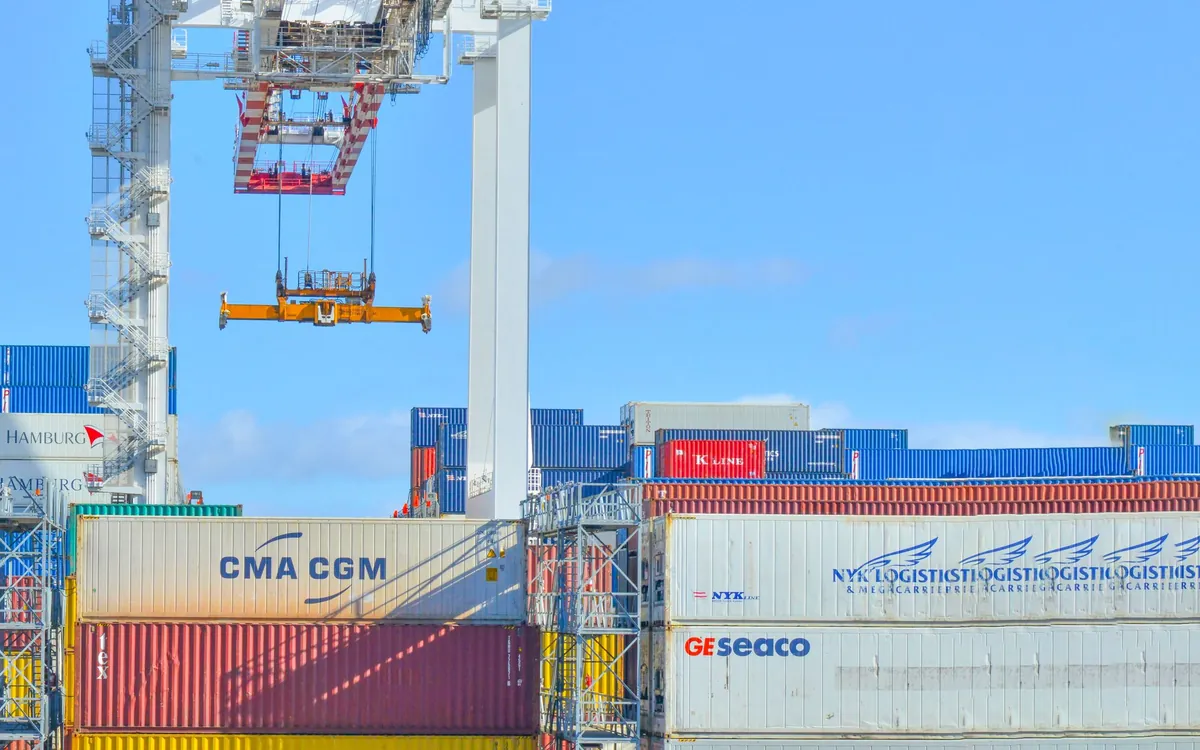 A gantry crane lowering a shipping container onto a stack at a terminal