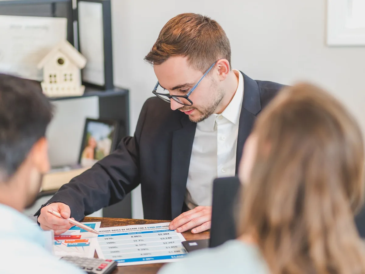 An agent walking a couple through property options at a table