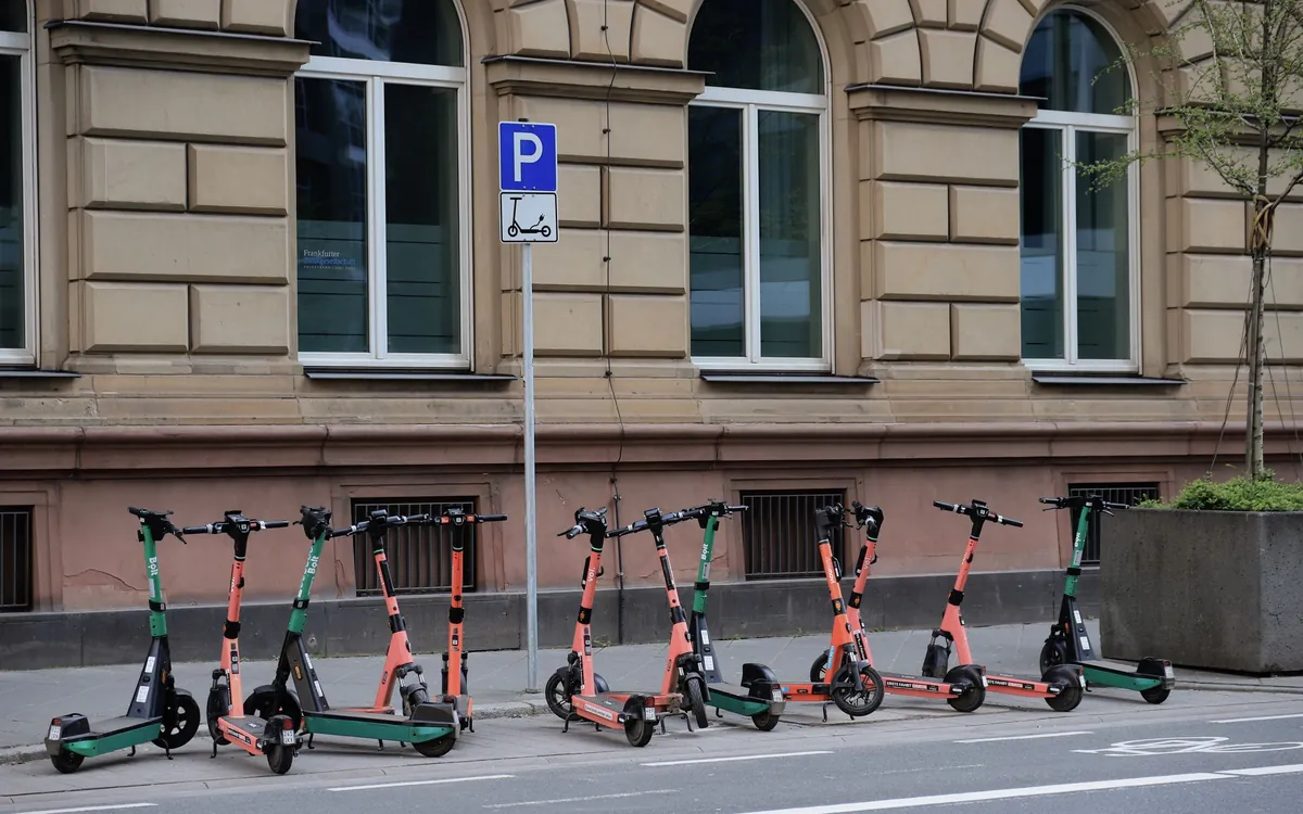 A row of shared e-scooters parked at a kerbside bay