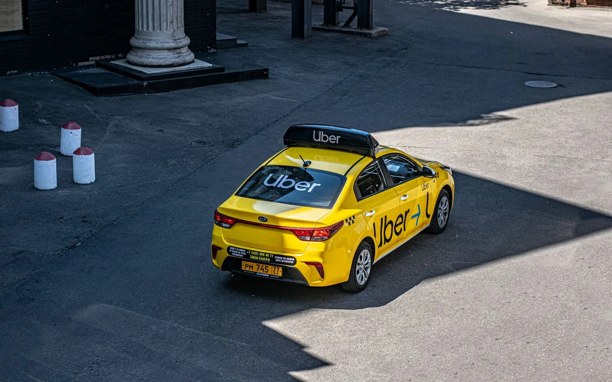 A yellow ride-hailing taxi seen from above on asphalt
