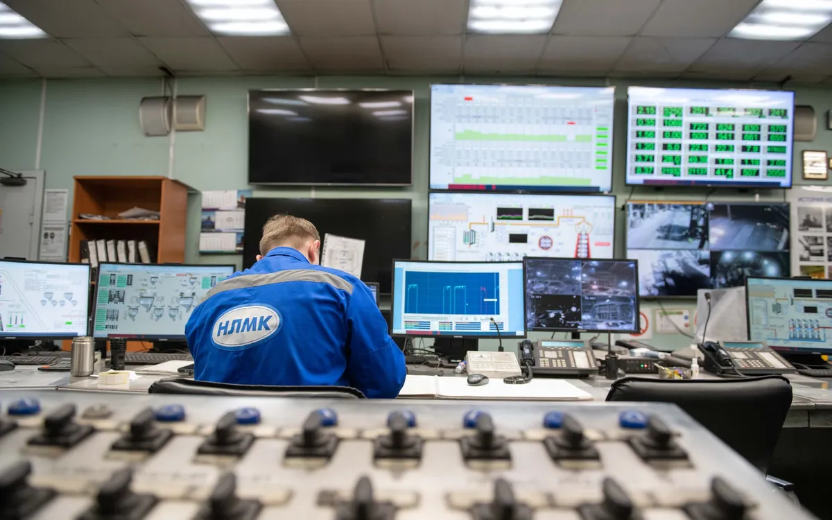 An operator at a control desk facing a wall of live monitoring screens