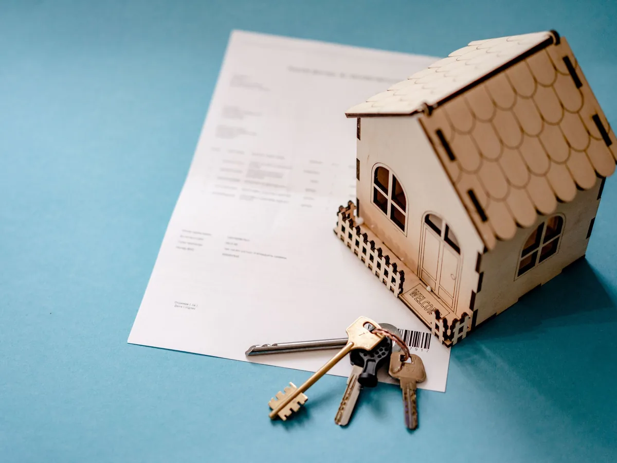 A model house, keys and a signed contract on a desk