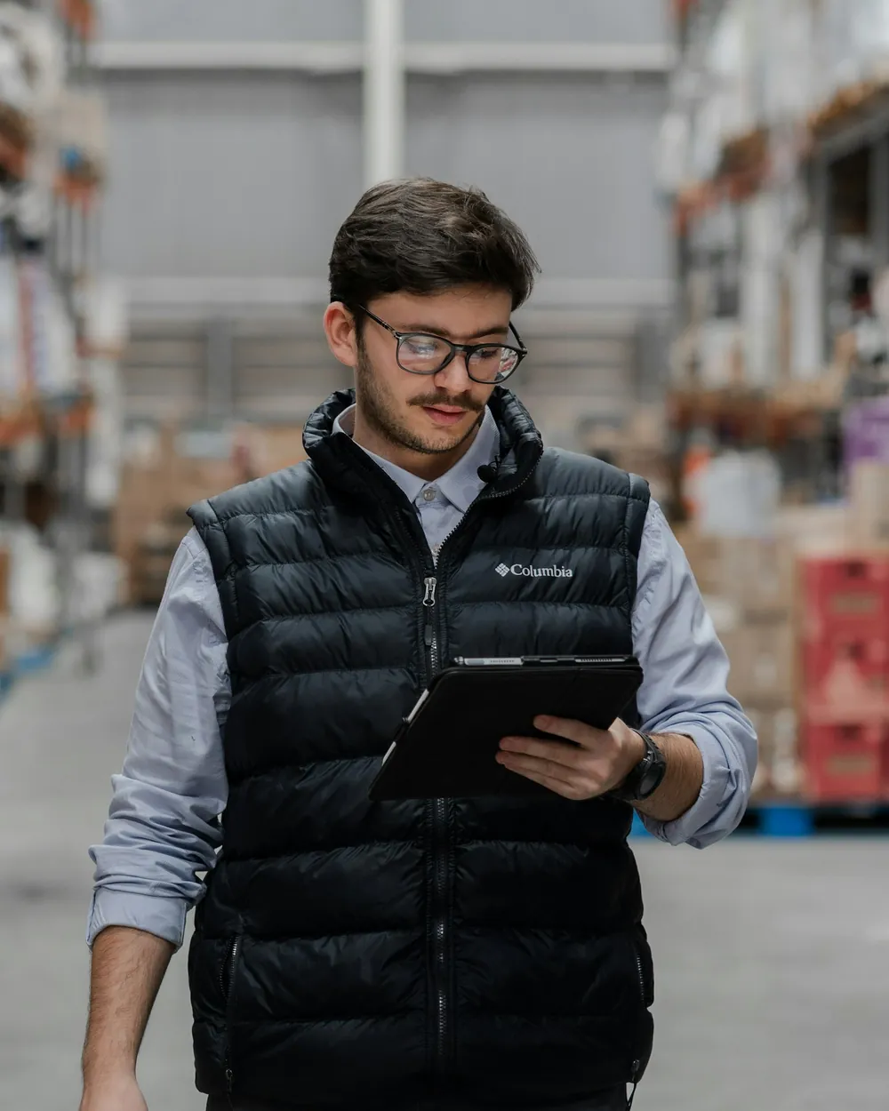 A store operator reviewing stock on a tablet in a distribution centre
