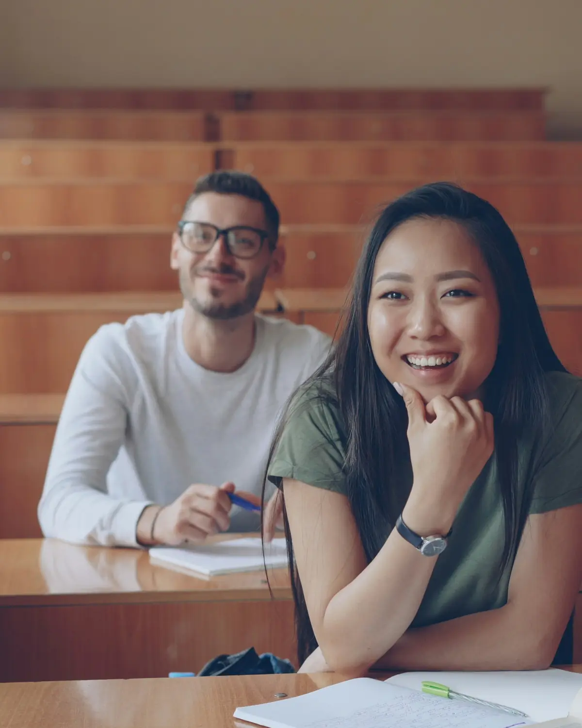 Two university students smiling in a lecture hall