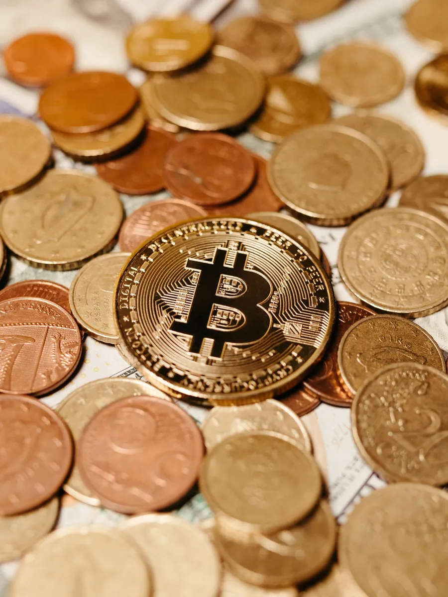 A gold bitcoin among a pile of mixed coins