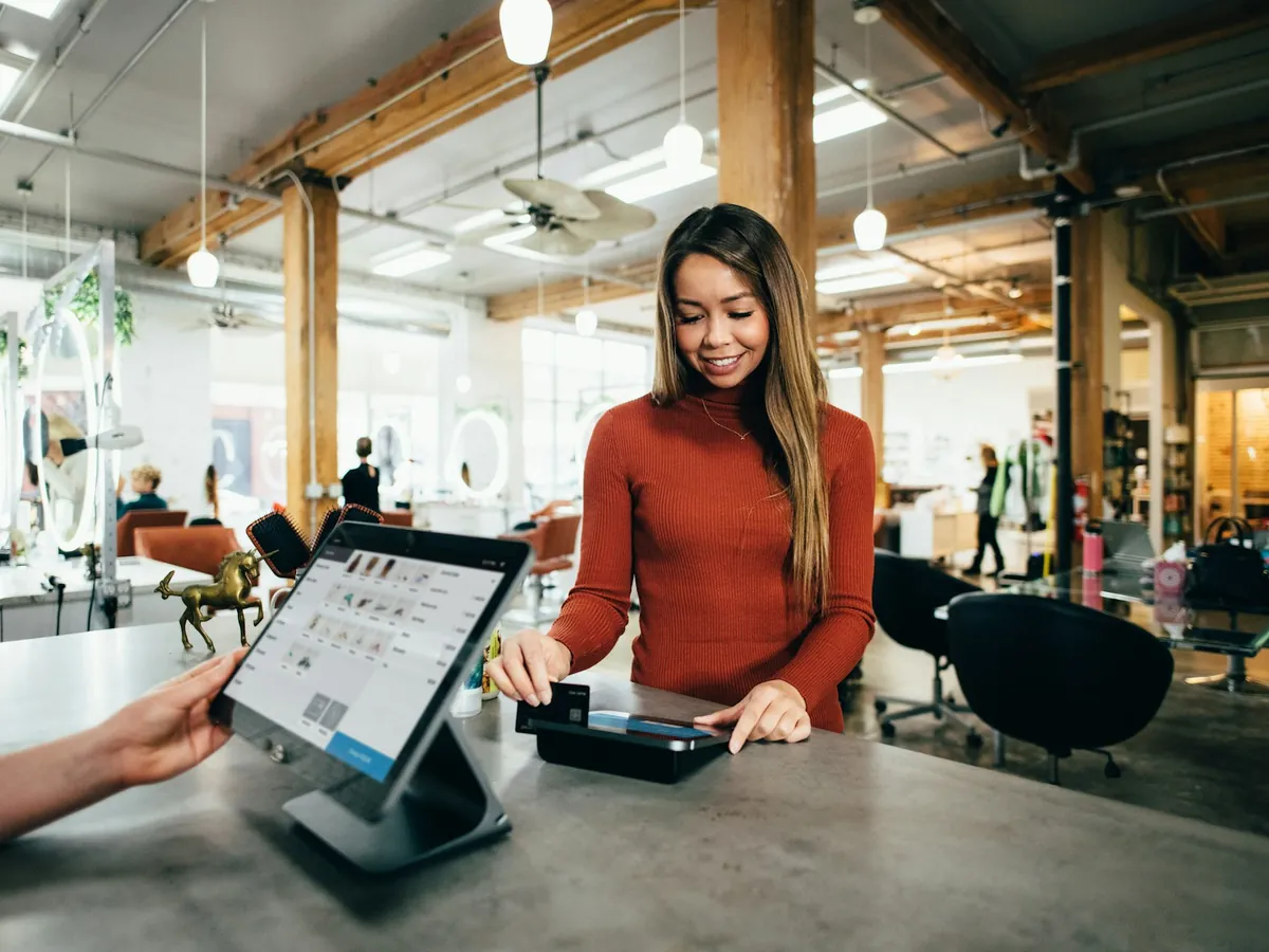 A shop assistant taking a card payment at a tablet point-of-sale counter