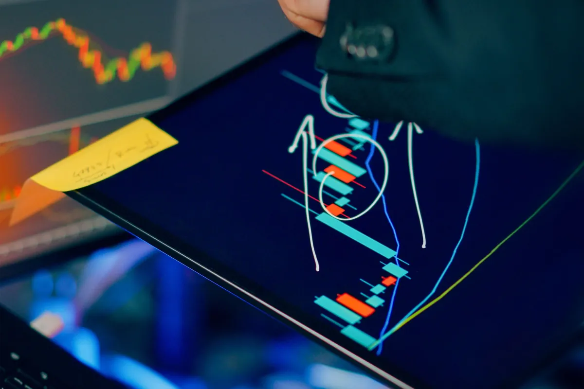 An investor comparing charts across a tablet and laptop